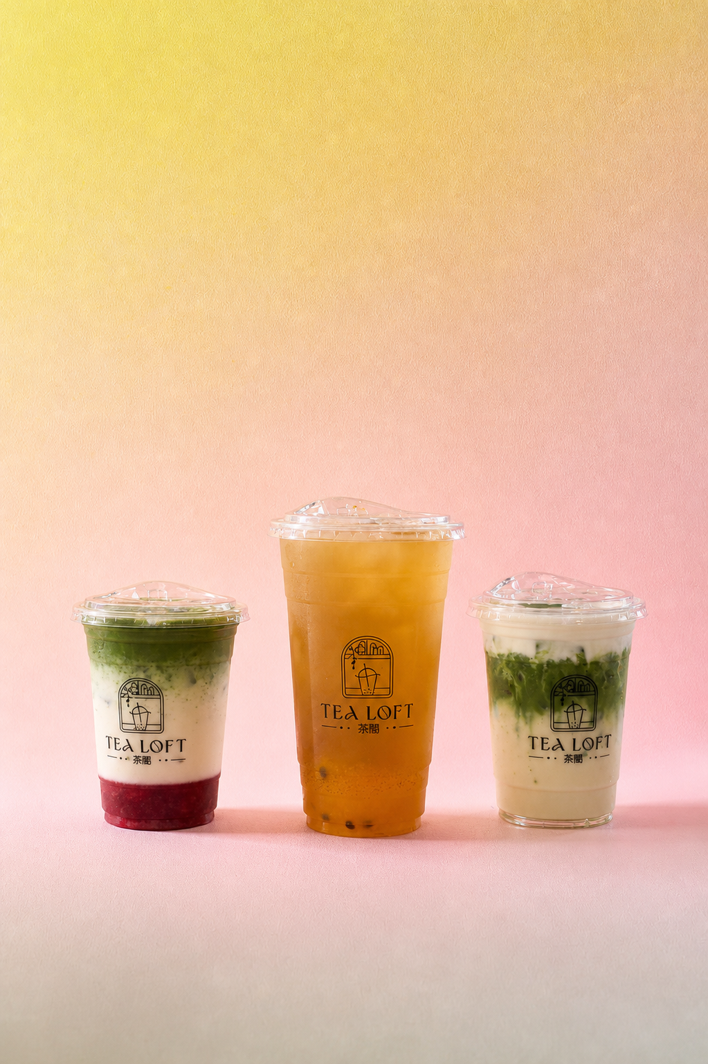 Three iced tea drinks in clear plastic cups with lids, lined up against a soft yellow-to-pink gradient background. The left cup is layered green, white, and dark red; the center cup is filled with amber-orange tea; the right cup is layered green and white with a dark red base.